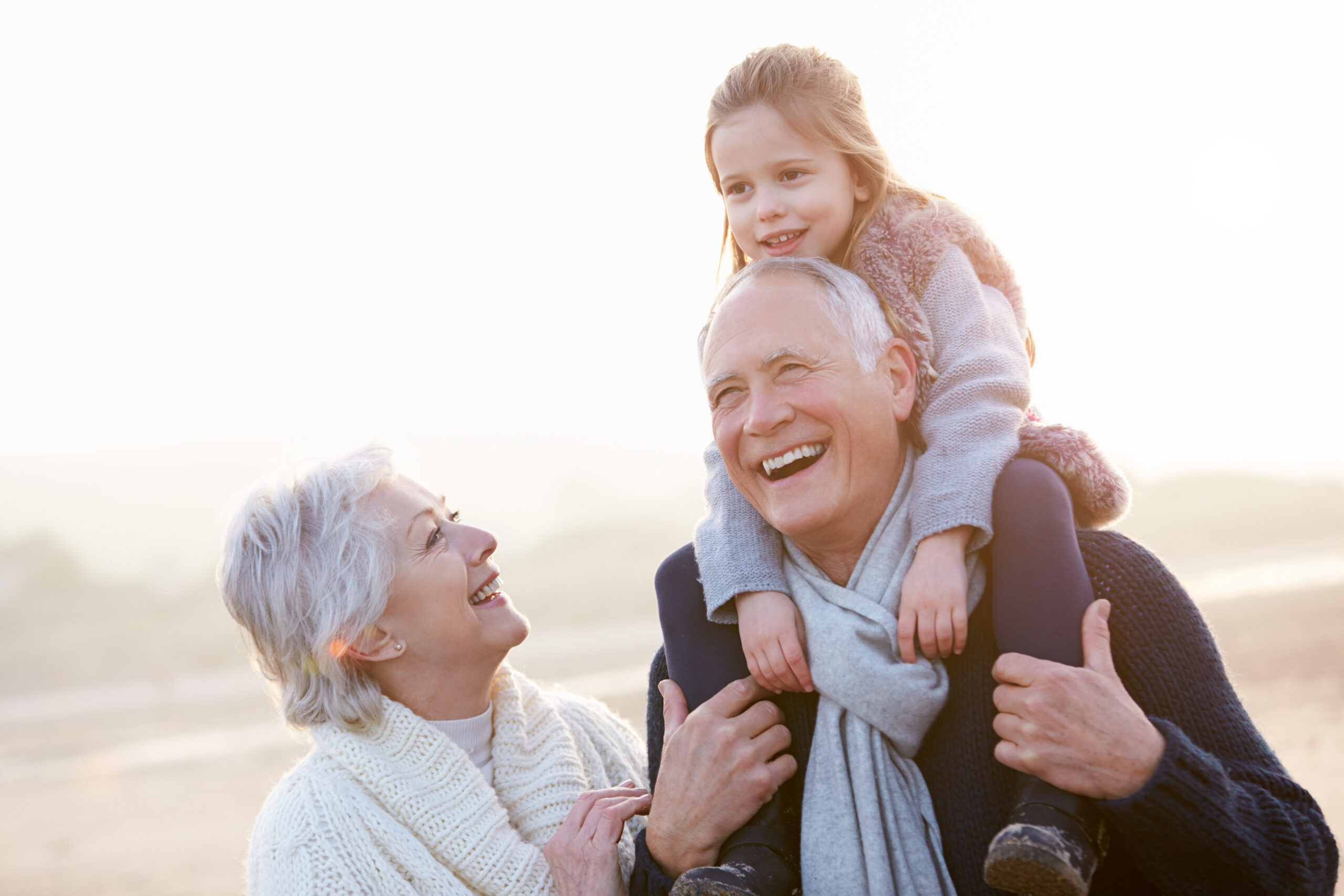 Grandparents,And,Granddaughter,Walking,On,Winter,Beach